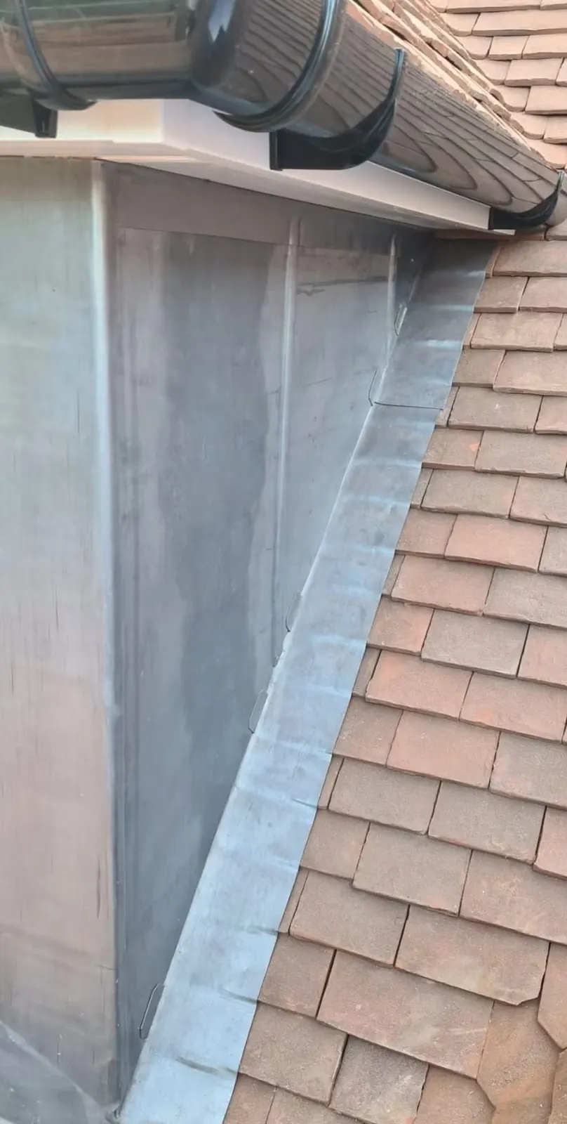 Dormer lead cheek and UPVC guttering on a tiled roof, Surrey
